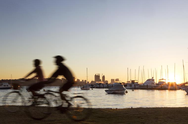 People ride on bikes with Perth city in the background.