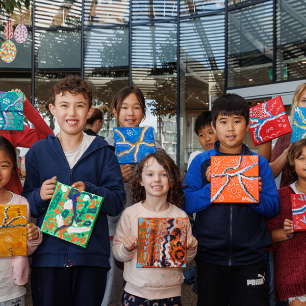 Justin Martin and children holding up artwork from an art workshop.