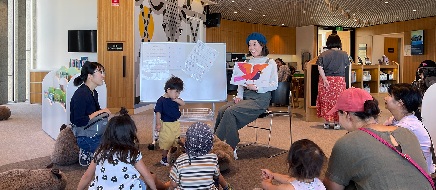 Japanese Storytime at the City of Perth Library, presenter reading picture book to children and parents.