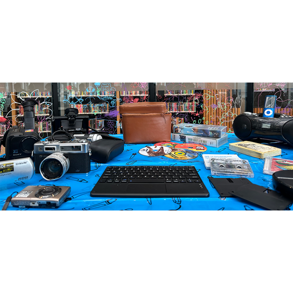 Table in the Library filled with retro tech and old fashioned equipment.