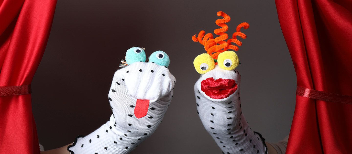 Dotty sock puppets with goggly eyes arranged on a puppet stage.  