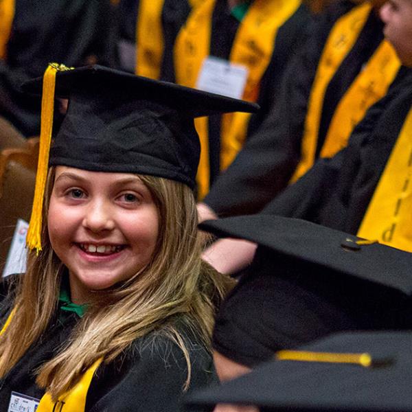 Children in university graduation gowns