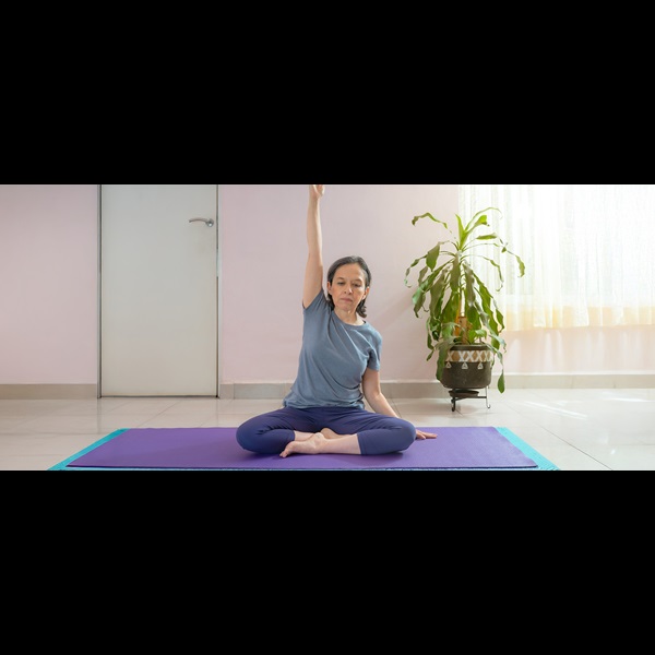 Older lady stretching on a yoga mat.