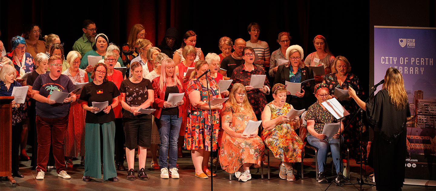 Participants in the Noongar Carols concert 2024 singing on stage with Gina Williams-Ghouse.
