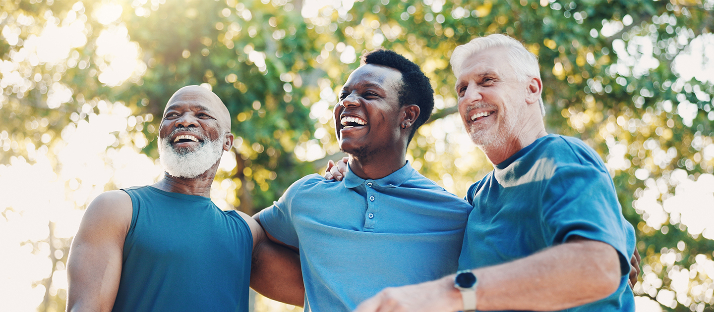 Senior men in blue shirts standing together in a park.