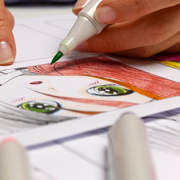 Close up shot of hands holding a marker and drawing Manga.