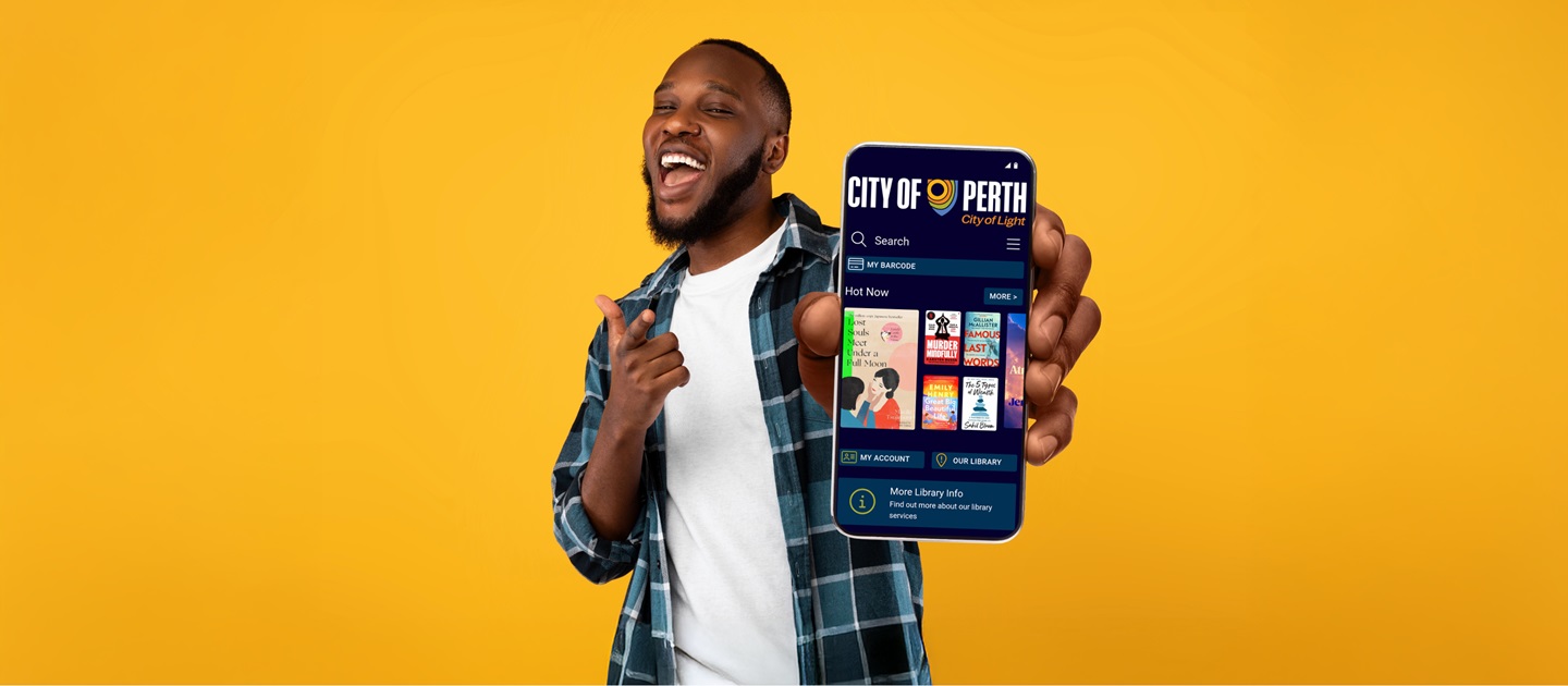 Handsome, cheerful man smiling into the camera and holding out his phone showing the screen with the City of Perth Library app on it. 