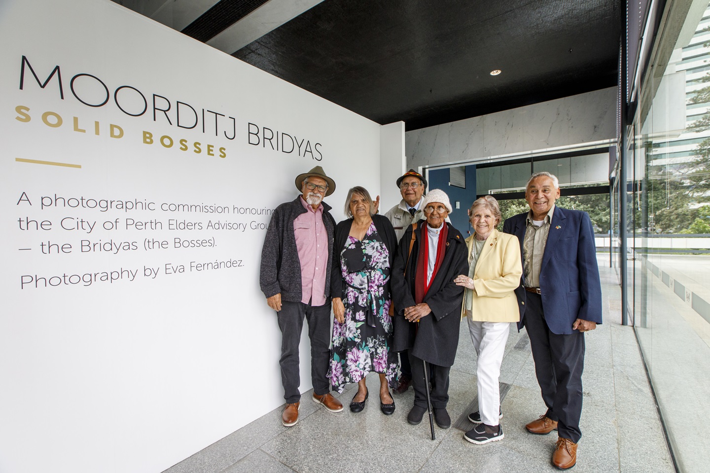 Aboriginal Elders pose next to portraits