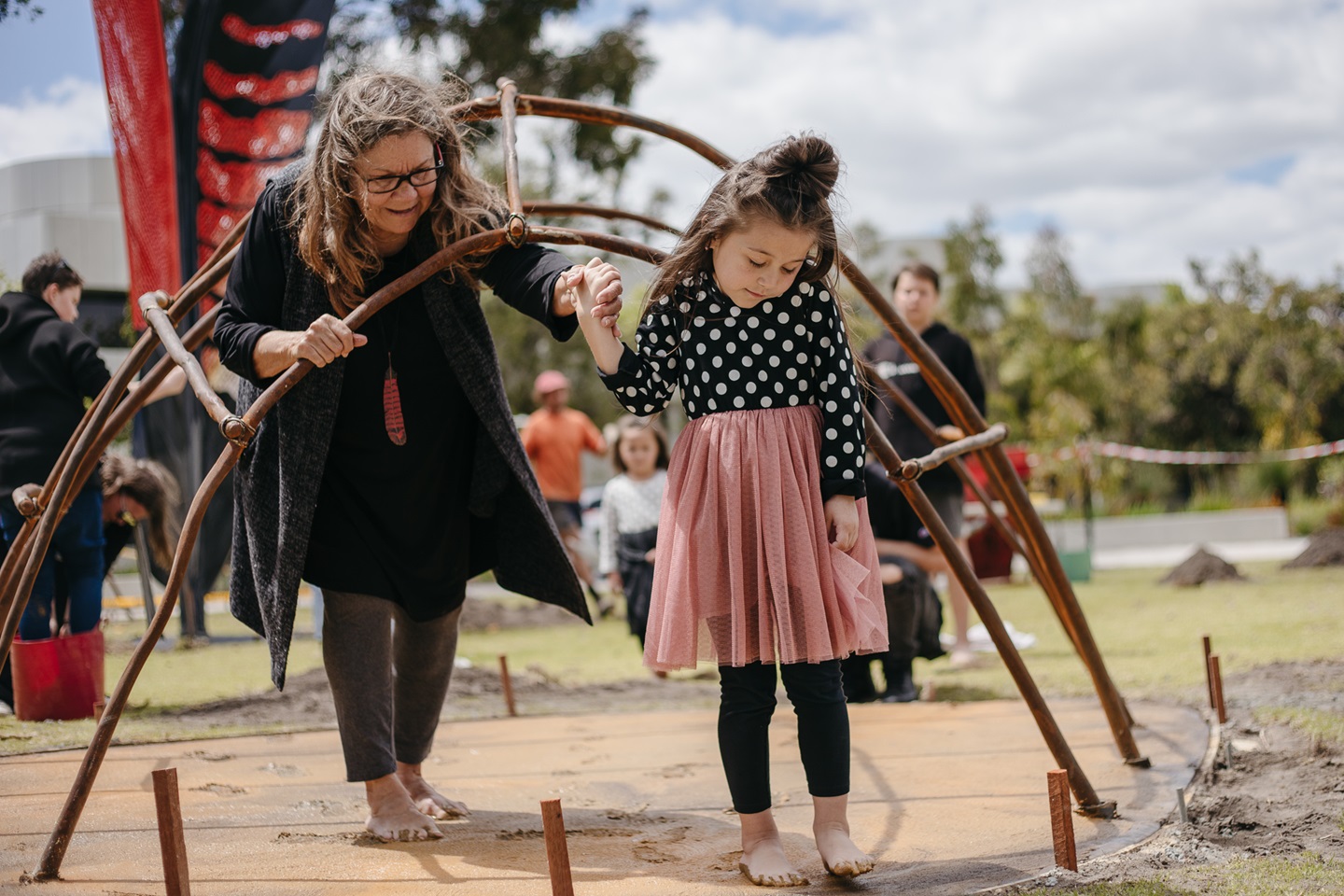 Artist holds the hand of little girl as they leave footprints in the cement