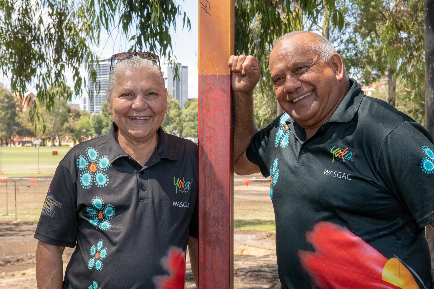 A woman and man lean on a pole in a park