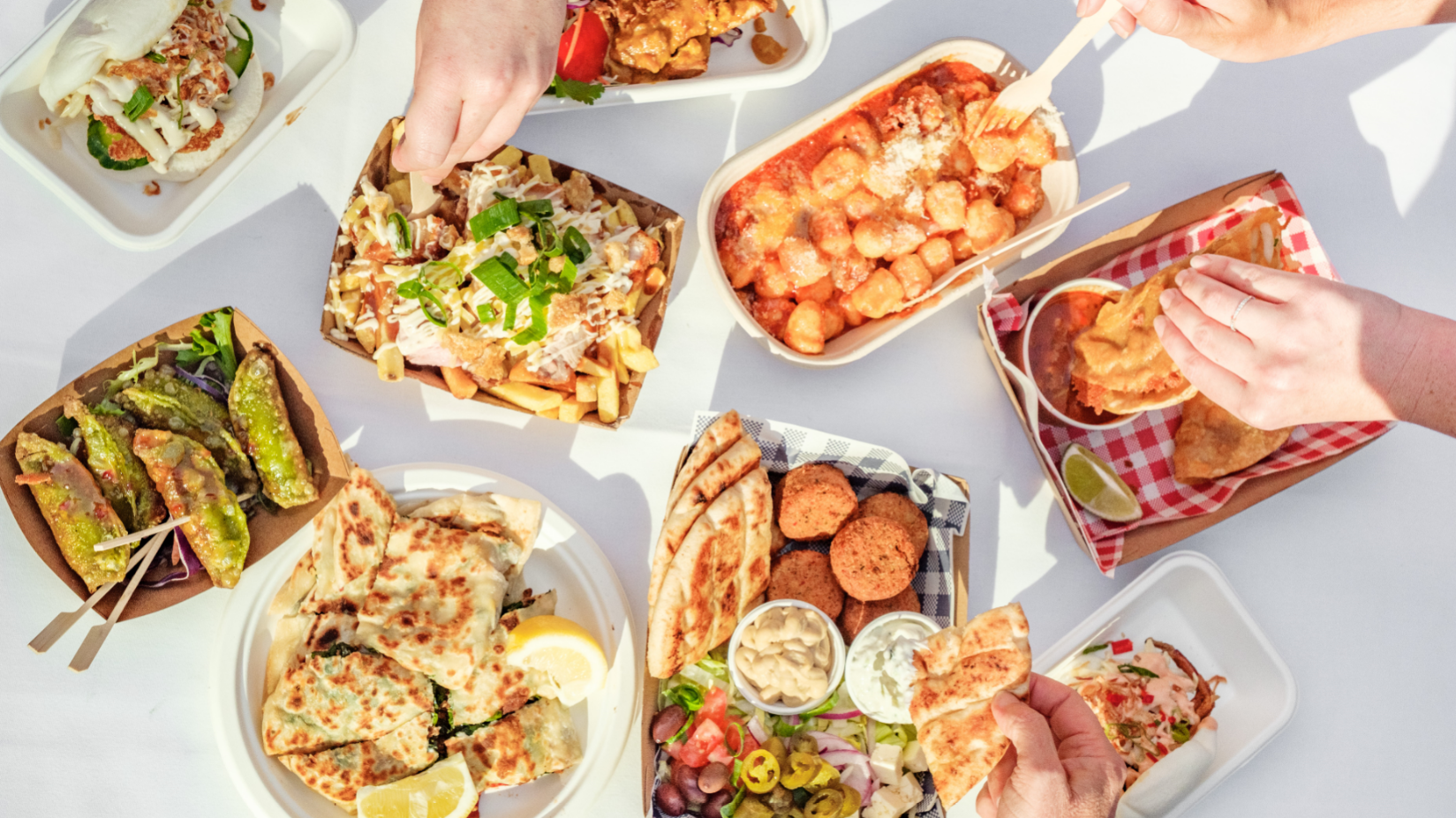 Hands grabbing food from food trucks at the Twilight Food Market.