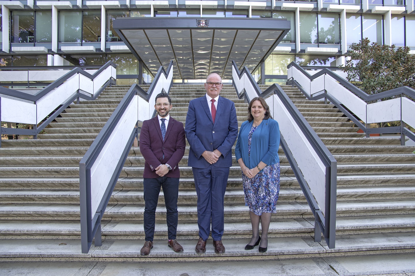 Three people stand outside a building