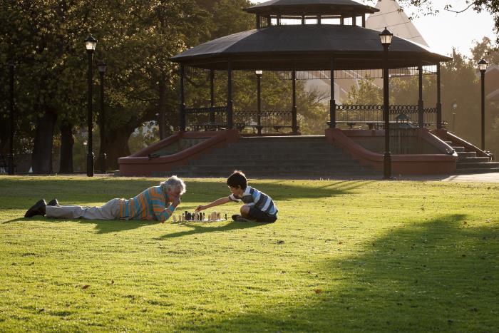 Russell Square Image of older man and grandchild playing chess on the lawn of Russell Square with the Gazebo in the background