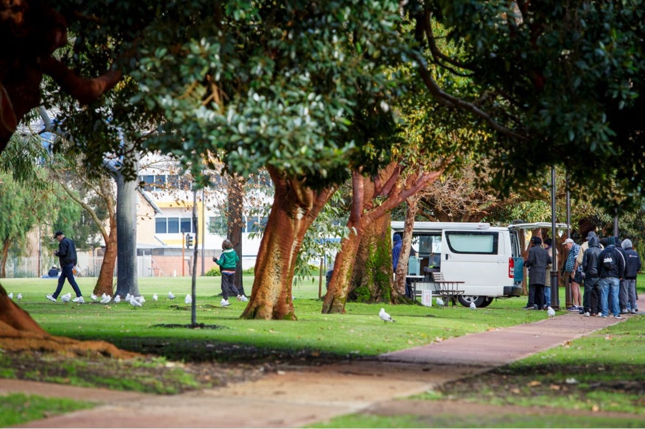 Food van feeding homeless in park.
