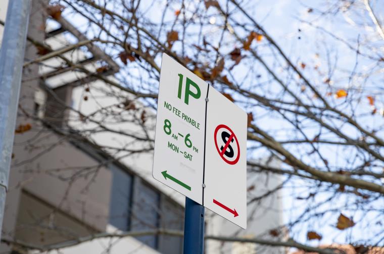 Parking sign that says '1P no fee payable' with tree branch in background