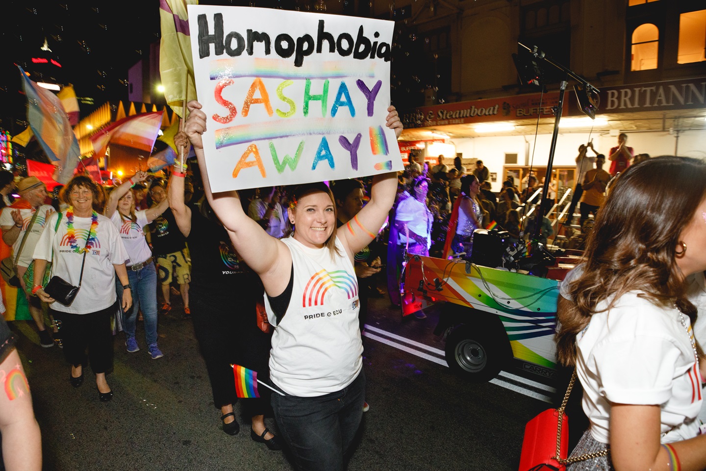 Person walking in Pride Parade holding sign that says "Homophobia Sashay Away!"
